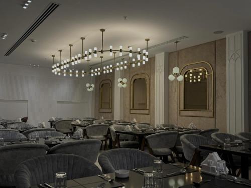 a dining room with tables and chairs and a chandelier at Ankawa Holiday Hotel in Erbil