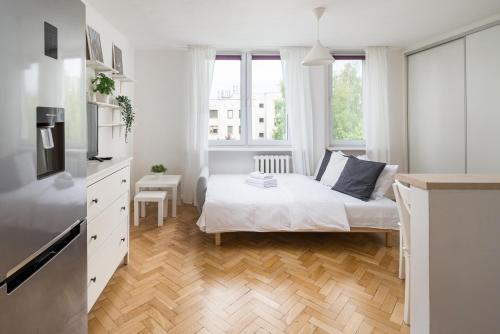 a white bedroom with a bed and a window at Urbanistów Cosy Studio in Warsaw