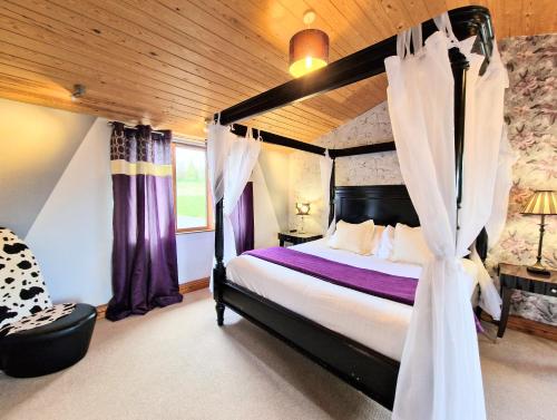a bedroom with a canopy bed with purple curtains at Ochil 8 with Private Hot Tub - Fife - Loch Leven - Lomond Hills in Kelty