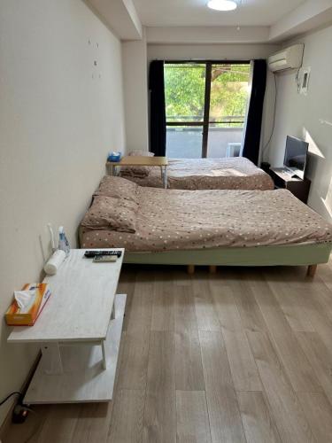 a room with two beds and a table and a desk at Wise Park Mukojima in Tokyo