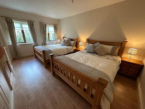 a bedroom with two beds and two windows at 'Emily' Deluxe Family Room in Foxford