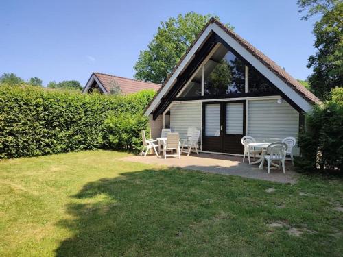 a house with a table and chairs in a yard at vrijstaande recreatiebungalow met slaapvide in Posterholt