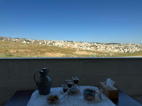 a table with glasses and a vase and a view of a city at Jerash City View in Jerash