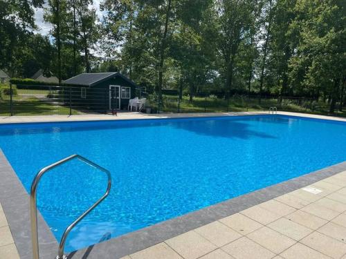 a large blue swimming pool with a metal hand rail at vrijstaande recreatiebungalow met slaapvide in Posterholt