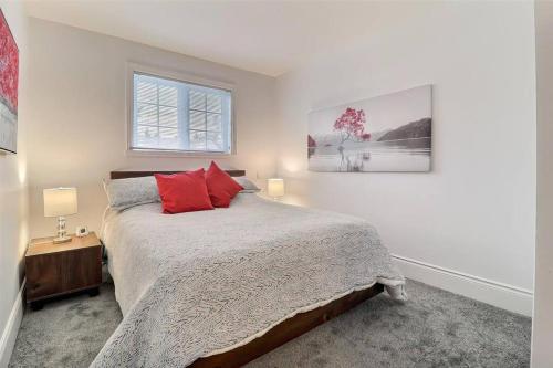 um quarto branco com uma cama com almofadas vermelhas em Chalet Saint-Sauveur with heated pool! em Saint-Sauveur-des-Monts