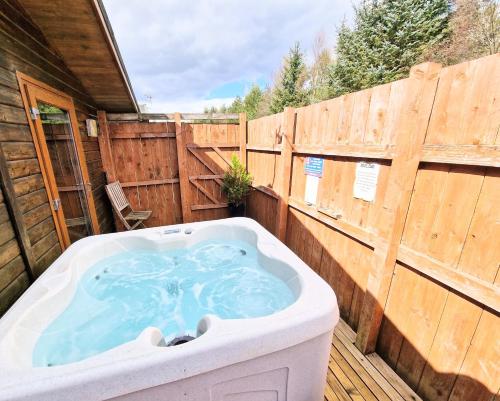 einen Whirlpool auf einer Terrasse mit einem Holzzaun in der Unterkunft Ochil 8 with Private Hot Tub - Fife - Loch Leven - Lomond Hills in Kelty