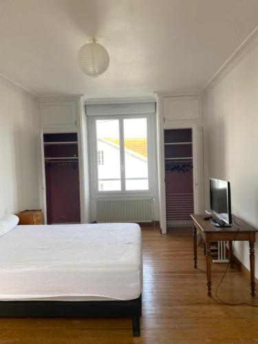 une chambre avec un lit, un bureau et une télévision dans l'établissement Élégante Villa centre ville Royan proche plages 3 chambres 3 grands lits, à Royan