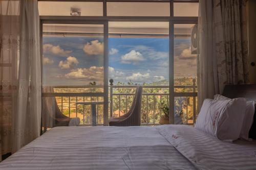 a bedroom with a bed and a large window at Vinetea Hotel in Kampala