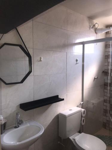 a bathroom with a toilet and a sink and a mirror at Residencial Estrela Guia 2 in Cabo Frio