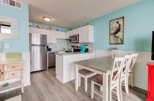 a kitchen with white cabinets and a table and chairs at 0306 Oceanfront Oasis by Atlantic Towers in Carolina Beach