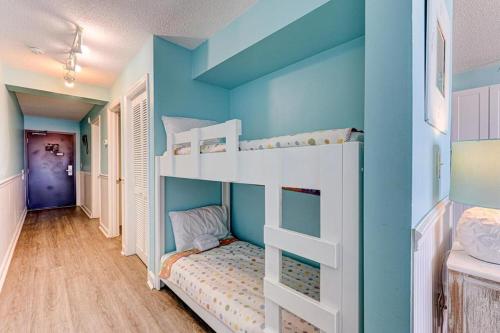 a room with two bunk beds and a blue wall at 0306 Oceanfront Oasis by Atlantic Towers in Carolina Beach