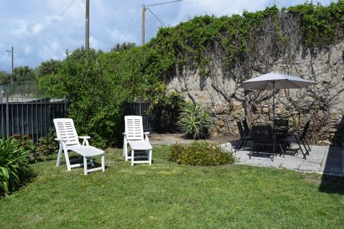 迪亞諾馬里納的住宿－Casa a Diano con giardino，草上一组椅子和一把伞