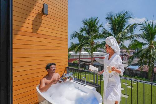 a man and woman in a bath tub on a balcony at Book a Bed Poshtel - SHA Plus in Phuket Town