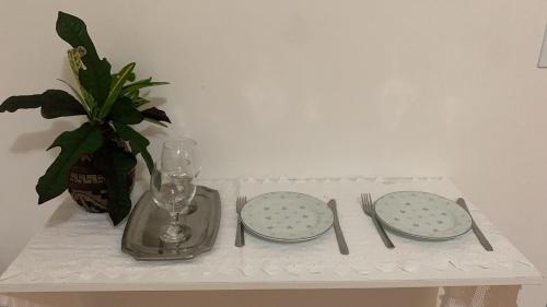 a table with two plates and a vase with a plant at Pousada Mar dos Sonhos in Paripueira