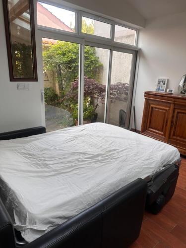 un lit dans une chambre avec une grande fenêtre dans l'établissement Maison proche Paris, à Colombes
