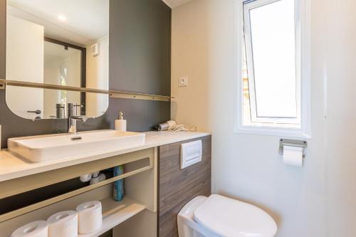La salle de bains est pourvue d'un lavabo, de toilettes et d'un miroir. dans l'établissement Domaine Ile d'or, bungalow Segur 8, à Saint-Raphaël