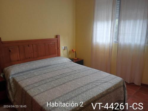 1 dormitorio con cama y ventana con cortina en Casa del Cerro, en Eslida