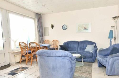 Una sala de estar con sofás azules y una mesa. en Ferienwohnung-Eilts-Whg-10, en Borkum