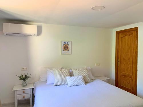 a bedroom with a white bed and a wooden door at Spanish charm guest apartment at villa with great location! in Las Lagunas Mijas