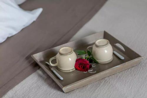 - deux tasses et une rose sur un plateau sur un lit dans l'établissement La Belle Du Marais, à Paris