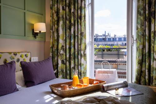 una camera d'albergo con un vassoio di arance su un letto con finestra di Hotel Clément a Parigi