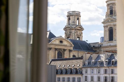 a view from a window of a building with a clock tower at Hotel Clément in Paris