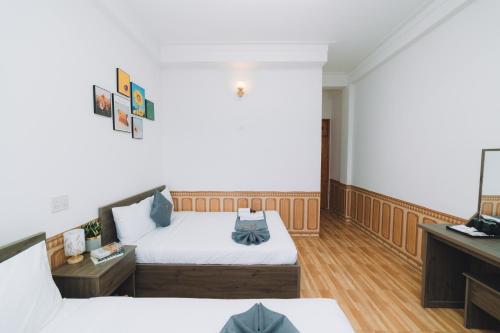 a hotel room with two beds and a television at AN TÂM House Đà Lạt in Da Lat