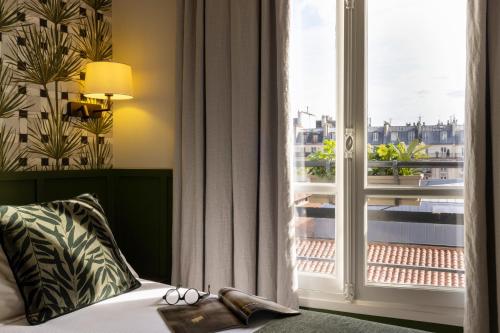 a bedroom with a bed and a large window at Hotel Clément in Paris