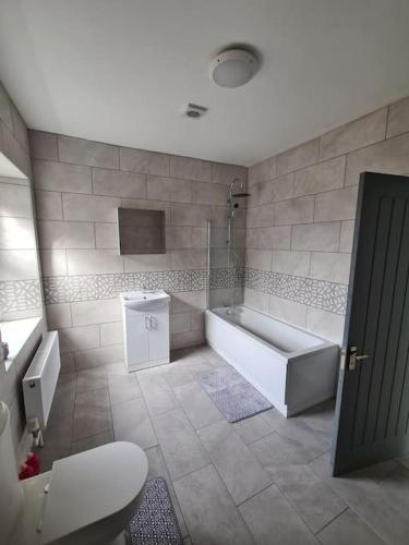 y baño con bañera, lavabo y aseo. en Newly Renovated Coastal Property, en Llanelli