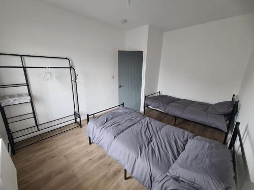 Habitación blanca con 2 camas y suelo de madera. en Newly Renovated Coastal Property, en Llanelli