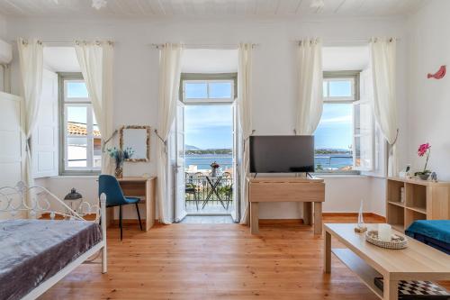 a bedroom with a bed and a tv and some windows at Martha's House in Spetses