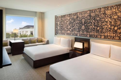 JW Marriott Hotel Muscat في مسقط: غرفة فندقية بسريرين واريكة