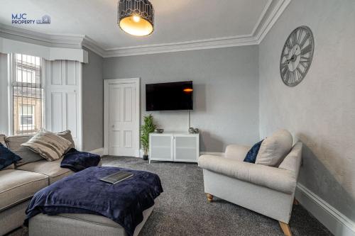 a living room with two couches and a flat screen tv at Turret Town House in Hawick