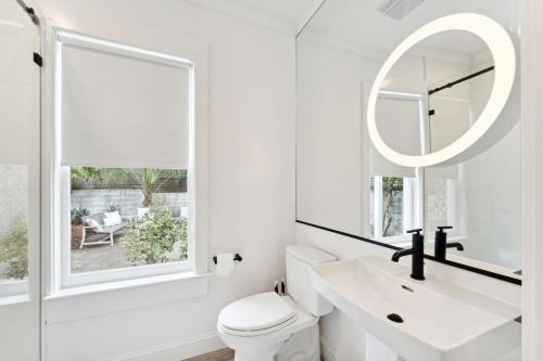 a white bathroom with a sink and a mirror at Downtown 3 Bedroom with Tons of Natural Light in Charleston