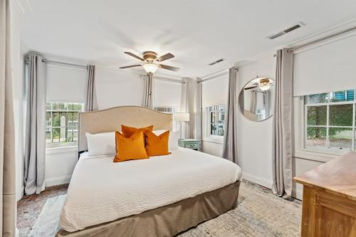 a bedroom with a bed with orange pillows and windows at Unique & Charming 2 Bedroom One Block to King St in Charleston