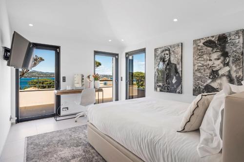 - une chambre blanche avec un grand lit et des fenêtres dans l'établissement Villa Paja, à Saint-Tropez
