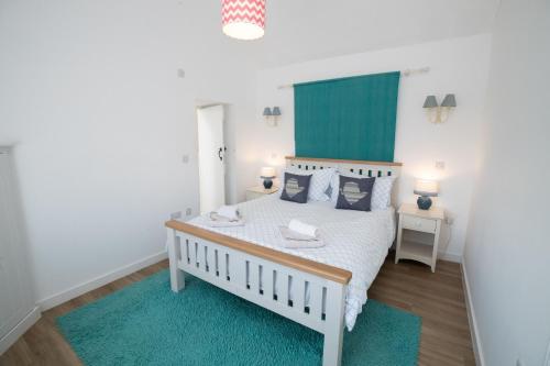 Un dormitorio con una cama blanca con almohadas azules. en Bron Haul, en Newborough