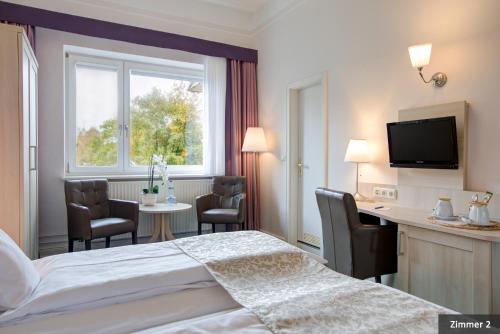 Habitación de hotel con cama, escritorio y ventana en Hotel See-Villa, en Malente