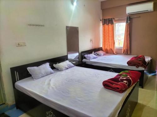 two beds sitting in a room with a window at Hotel Shobha and Tent House in Patrātu