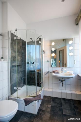 a bathroom with a shower and a toilet and a sink at Hotel See-Villa in Malente
