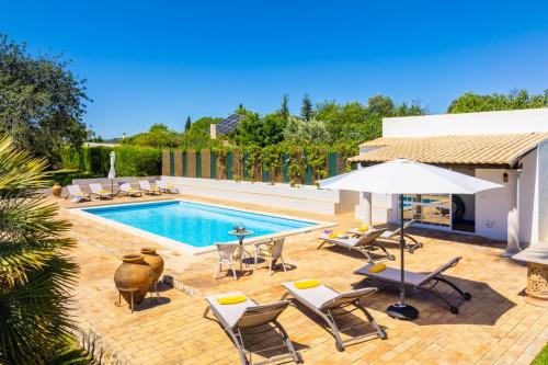 a swimming pool with lounge chairs and an umbrella at Casa do Carmo in Moncarapacho
