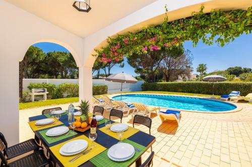 a patio with a table and chairs next to a swimming pool at Villa Cavaco in Vilamoura