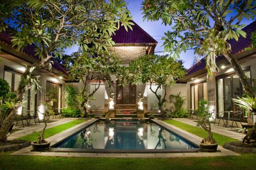 an exterior view of a house with a swimming pool and trees at Sindhu Mertha Suite in Sanur