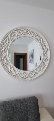 espejo circular en una pared blanca con sofá en Sister's home, en Iglesias