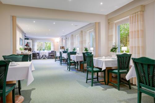 a dining room with white tables and green chairs at Hotel See-Villa in Malente
