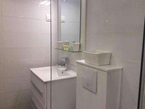 ein weißes Badezimmer mit einem Waschbecken und einem Spiegel in der Unterkunft Une fenêtre sur la mer in Le Gosier