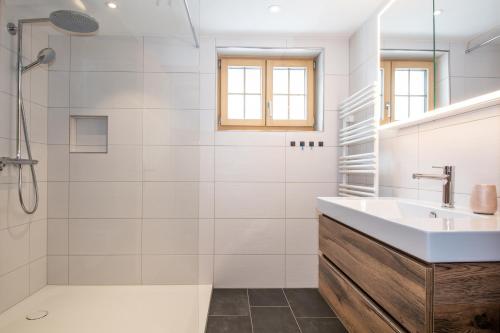 uma casa de banho branca com um lavatório e um chuveiro em Am Strubelweg em Adelboden