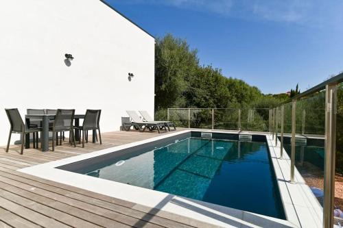 - une piscine sur une terrasse avec une table et des chaises dans l'établissement Villa La Rondina vue mer, piscine et plage à pied., à Zonza