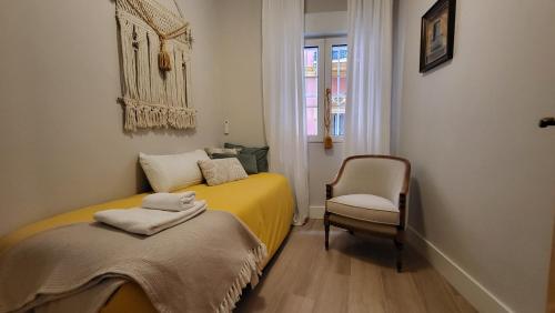 a small bedroom with a yellow bed and a chair at RentalSevilla en la Plaza del Salvador in Seville