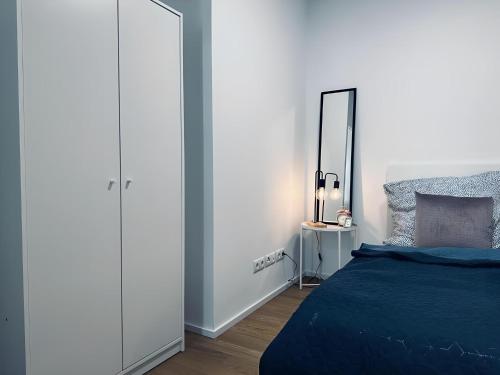 a bedroom with a blue bed and a mirror at Apartment ARTIC I Cityblick & Komfort in Nordhorn